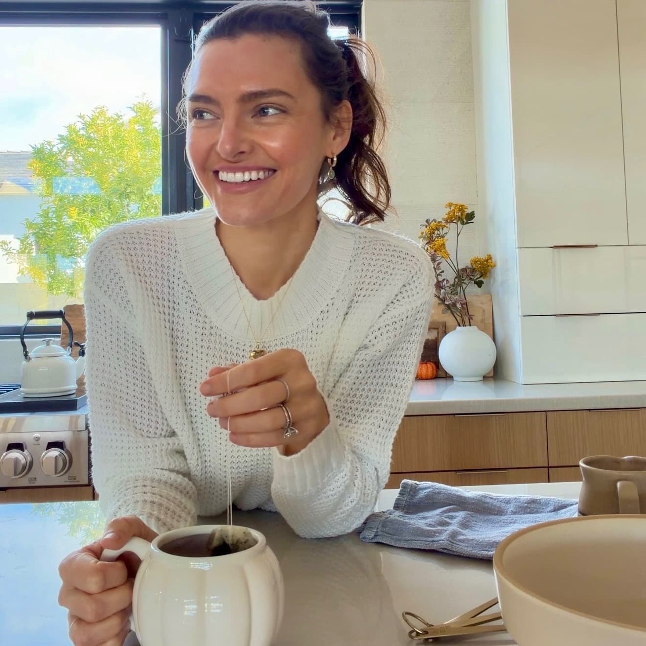 Angela Heckler smiling in her kitchen while making tea