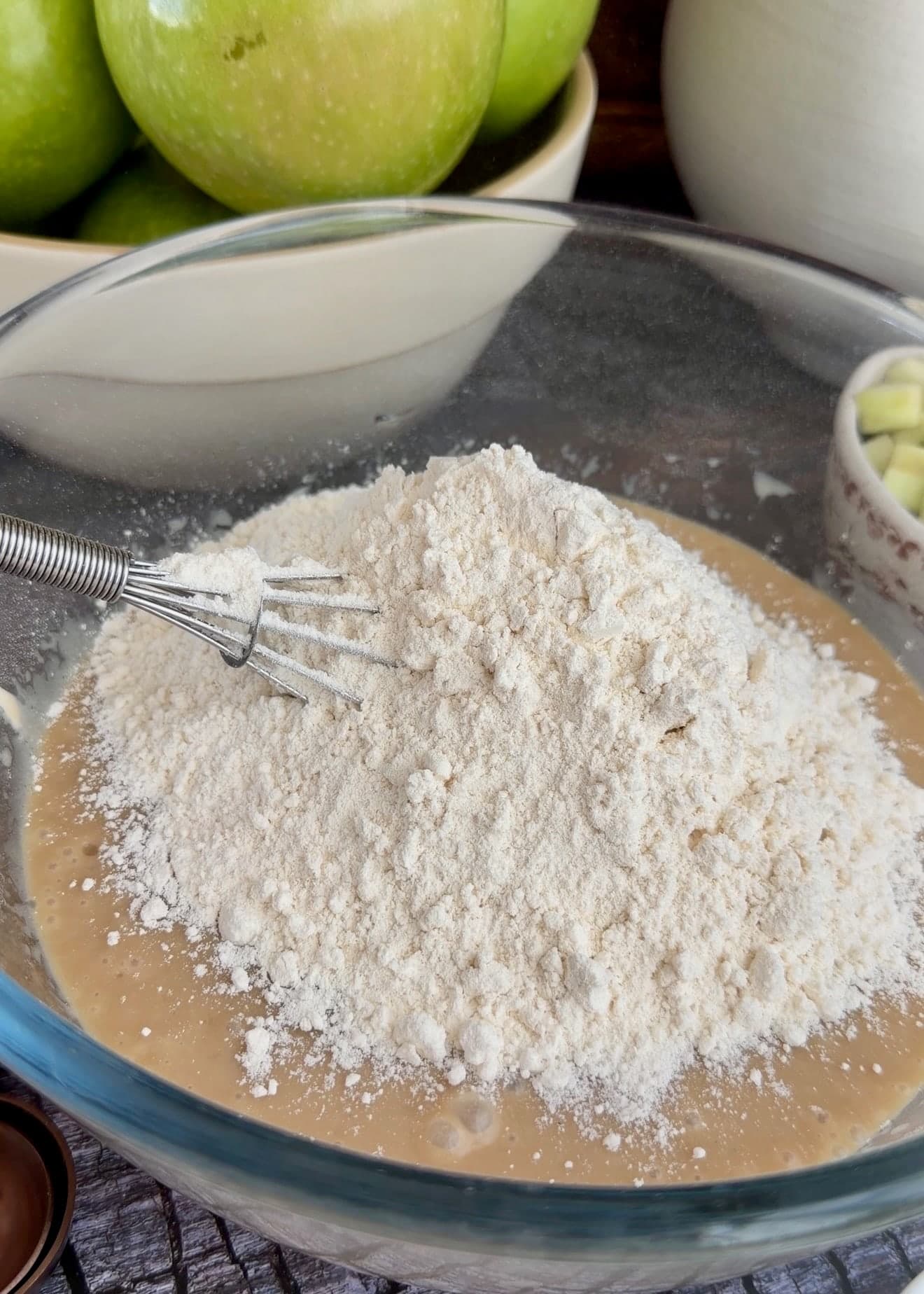 Flour mixture piled over the wet cake ingredients with a whisk in the bowl