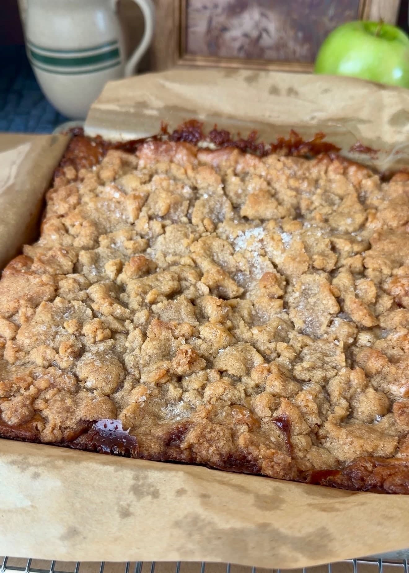 Baked coffee cake with golden crumble and dark caramelized edges inside its parchment