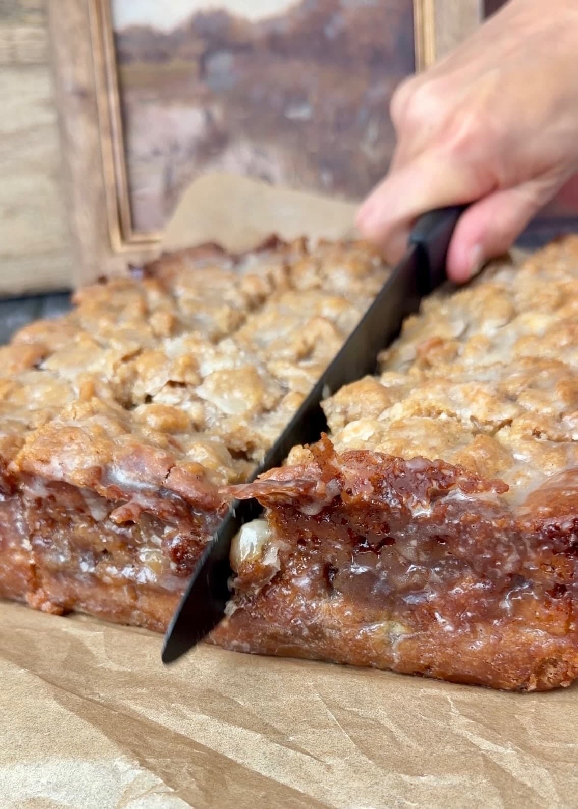 A knife beside a deeply browned coffee cake edge under a thin layer of glaze