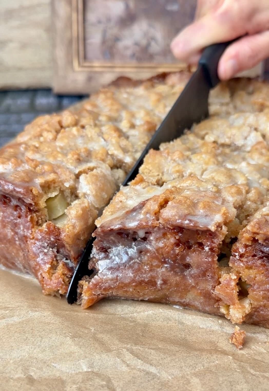 A close view of the knife cutting through a thinly glazed caramelized cake edge