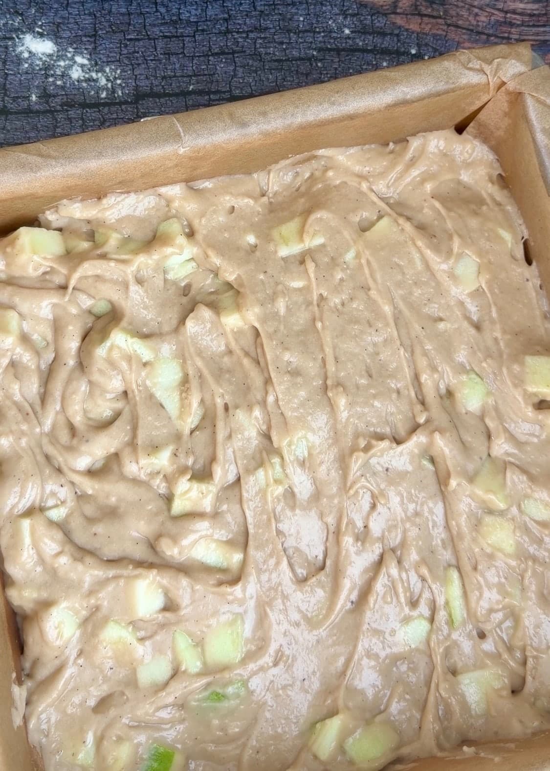 An even layer of apple batter covering the bottom of the lined pan