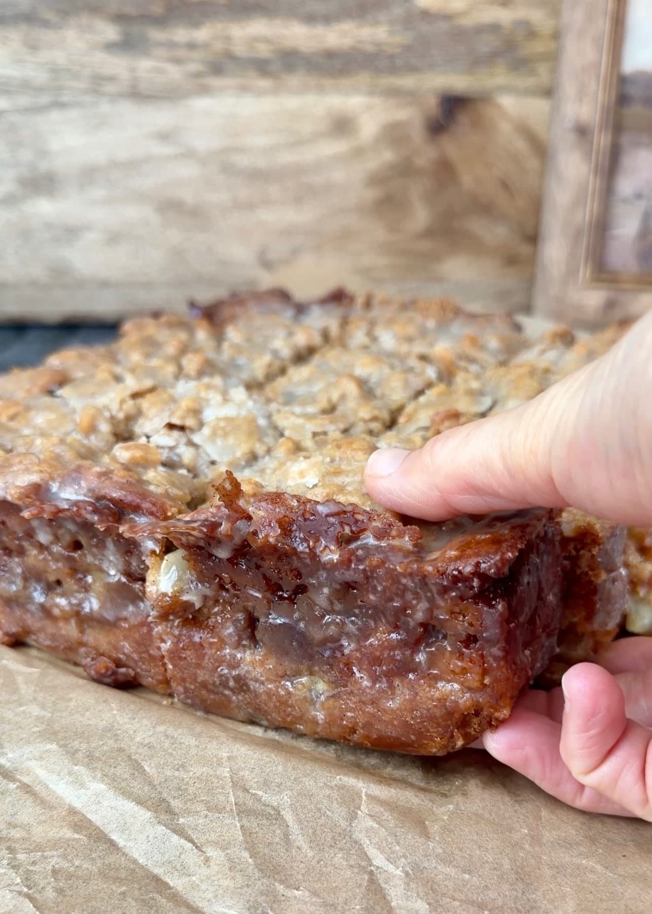 Hands lifting a corner piece from the sliced coffee cake
