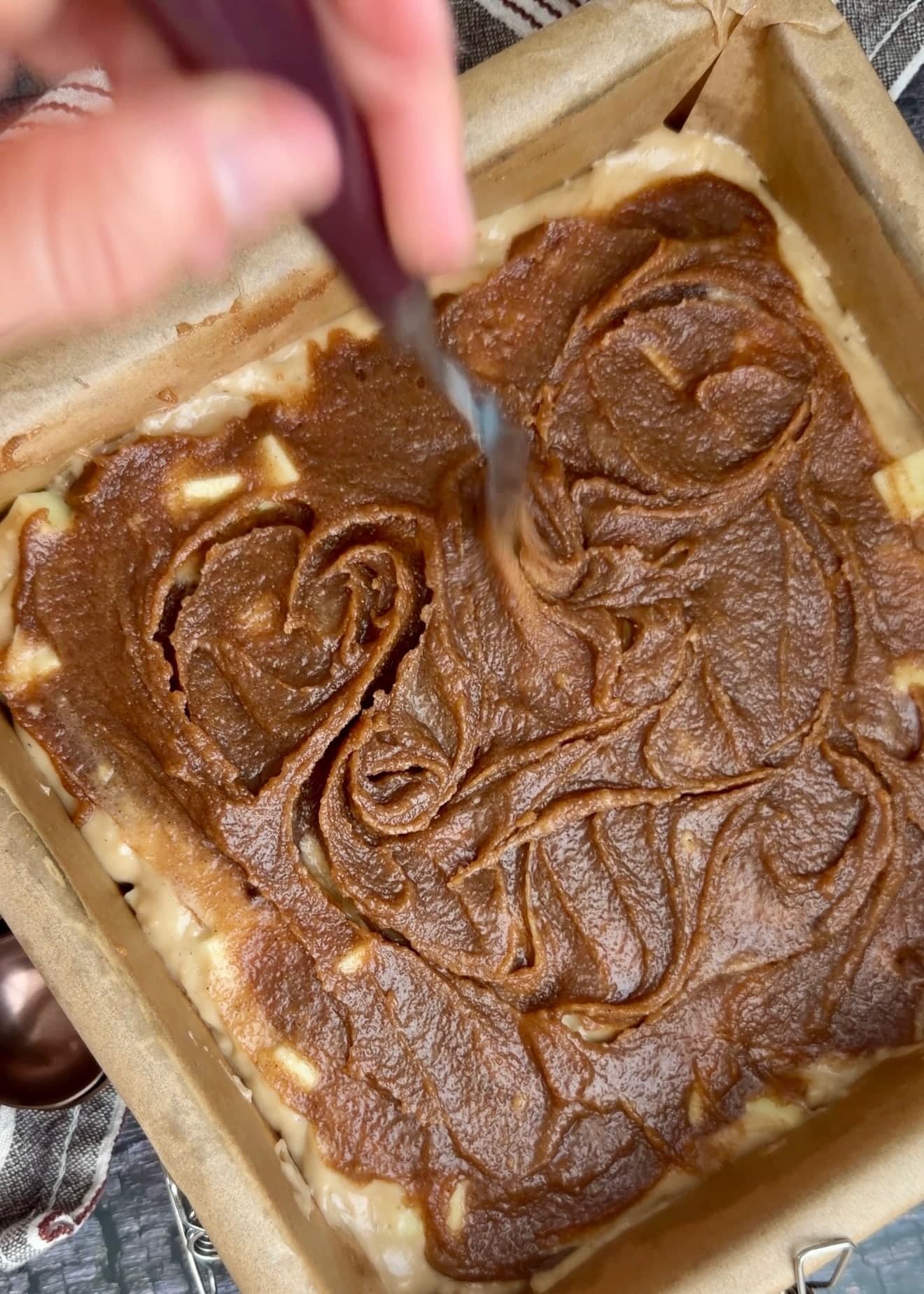 A knife making shallow swirls through the cinnamon layer