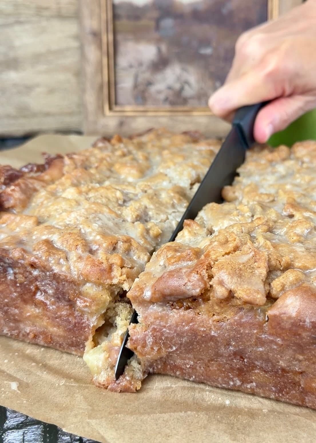 A knife cutting down through the glazed coffee cake