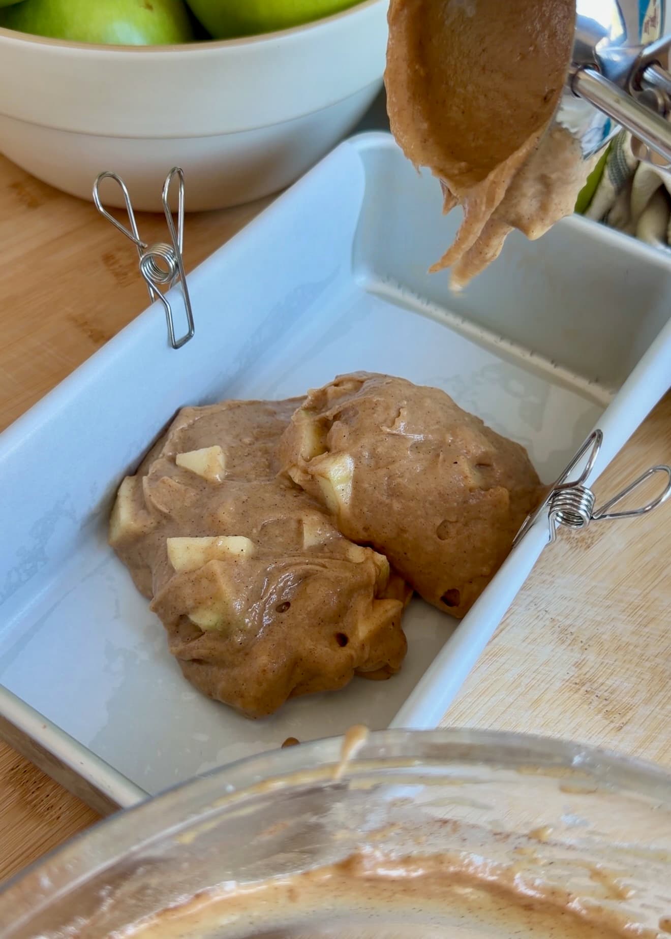 First layer of apple batter in a parchment-lined loaf pan