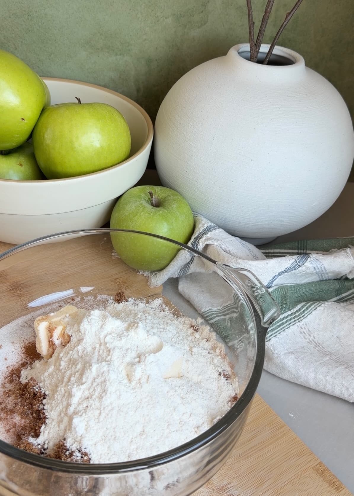 Cinnamon streusel ingredients in a glass bowl beside Granny Smith apples