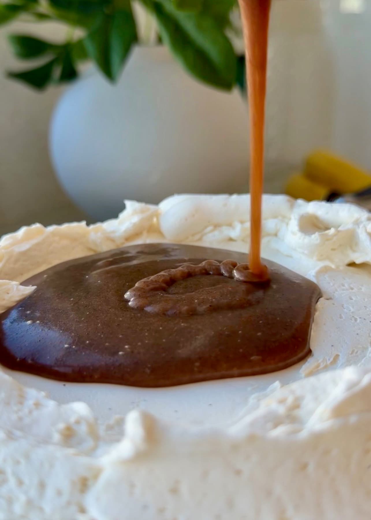 Cinnamon filling pouring inside a cream cheese frosting dam
