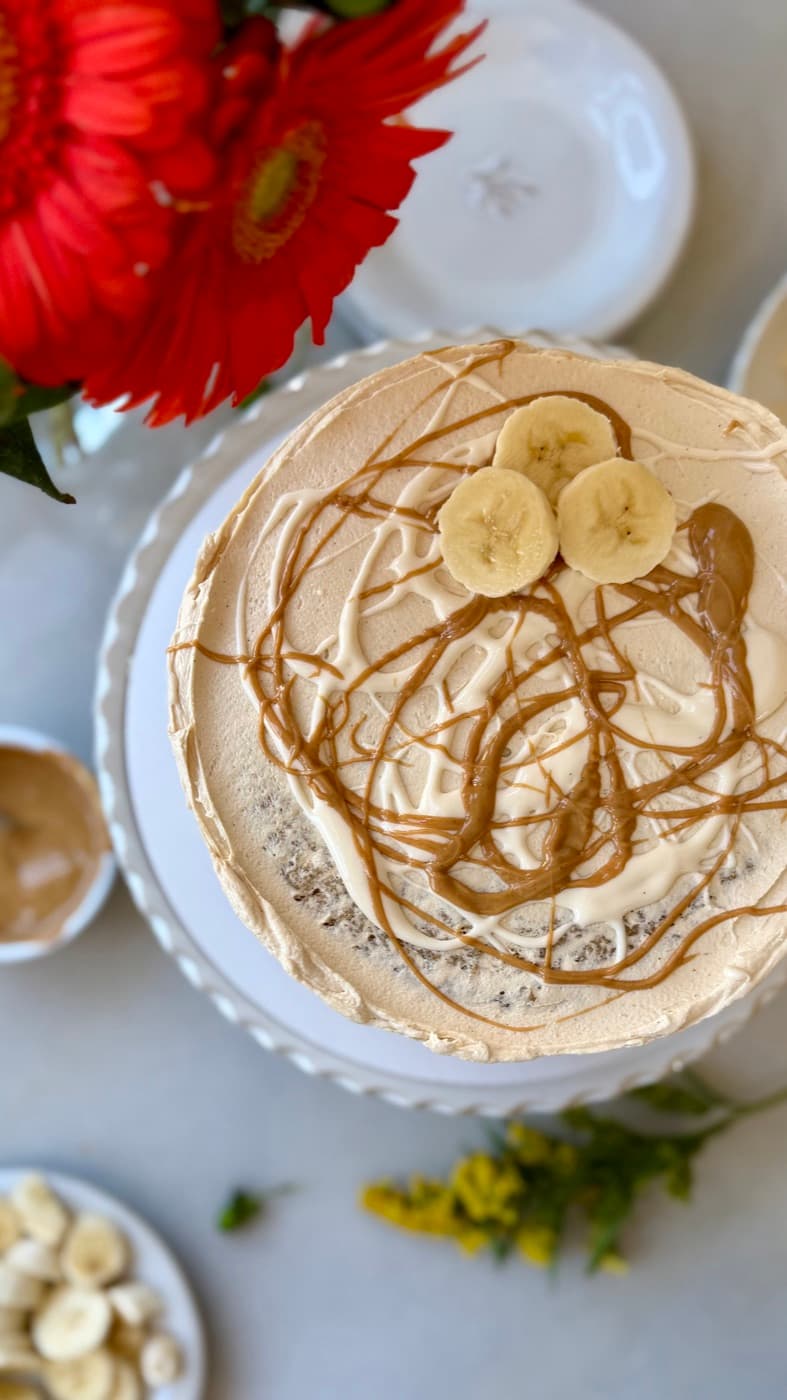 Overhead view of a finished cake with peanut butter drizzle and banana slices
