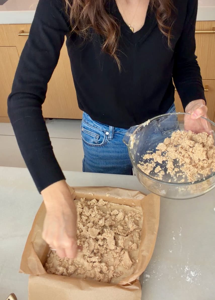 Chilled crumble being scattered over the banana cake batter