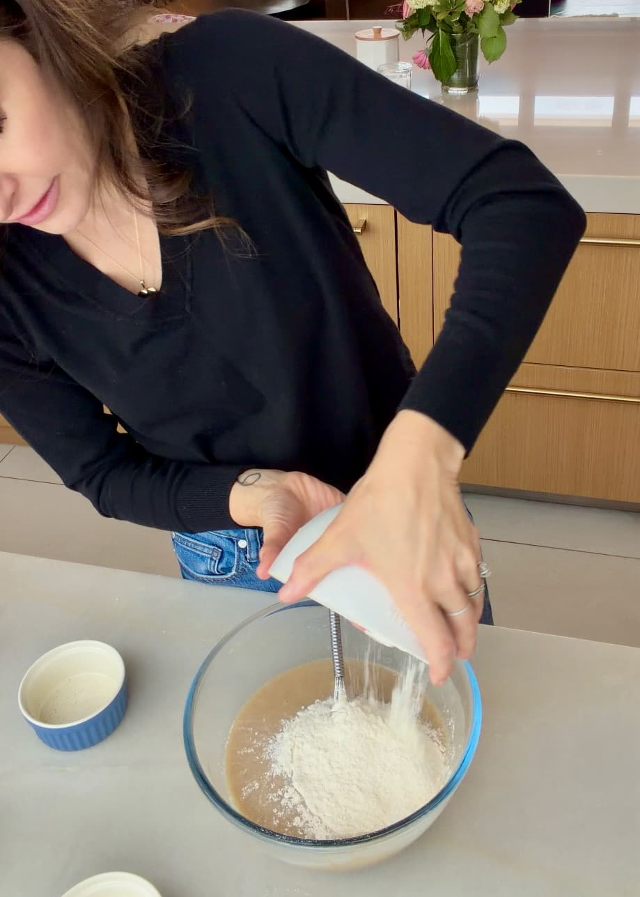 Flour mixture being tipped over the wet banana cake ingredients