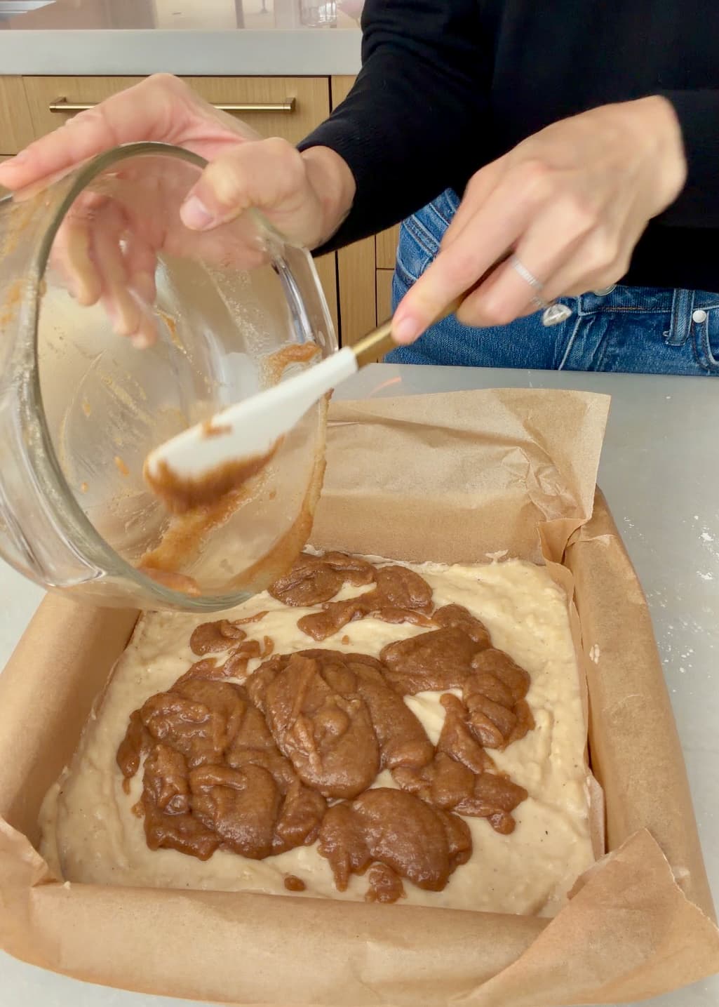 Cinnamon filling being spooned from a bowl over banana cake batter