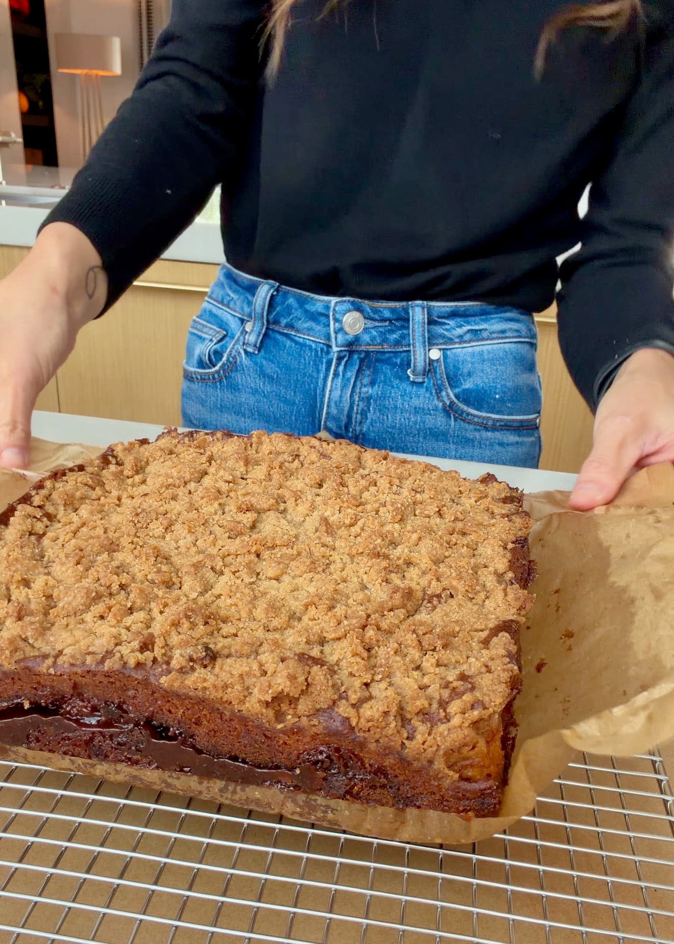 The baked cake resting on a wire rack with parchment at its sides