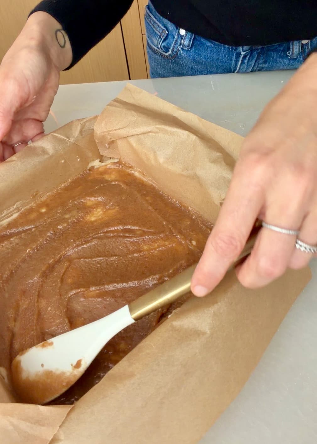 A spatula taking the cinnamon filling to the parchment-lined edge