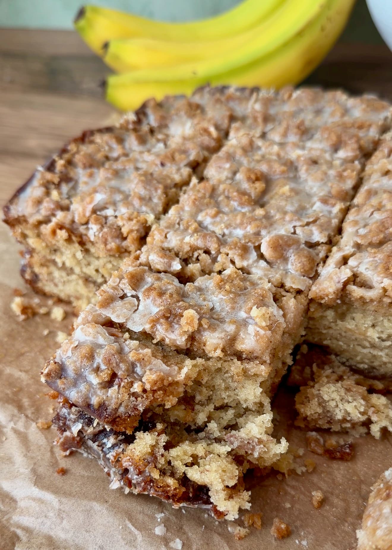A cut square of glazed banana coffee cake showing the interior crumb