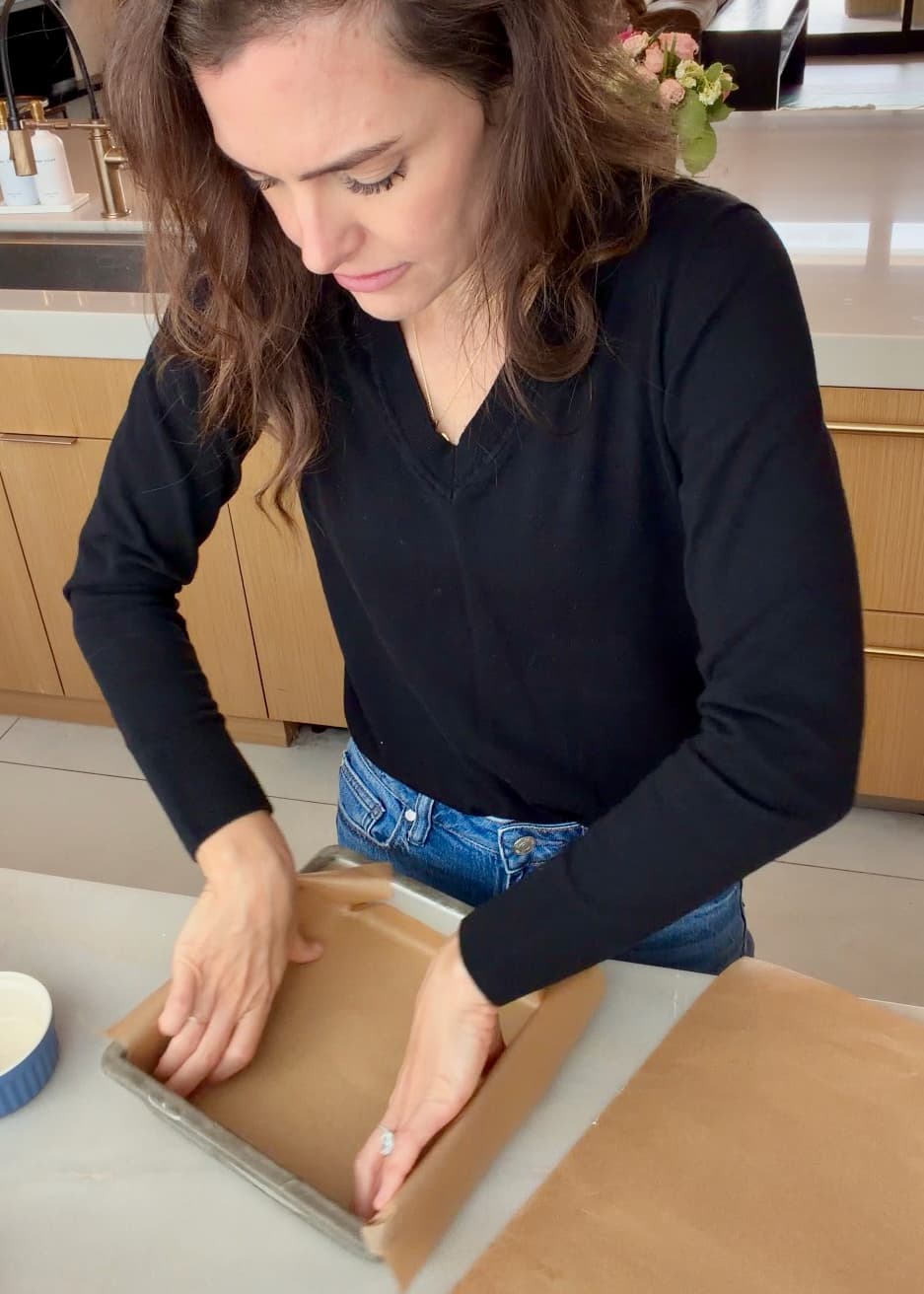 Angela pressing parchment into a square metal pan
