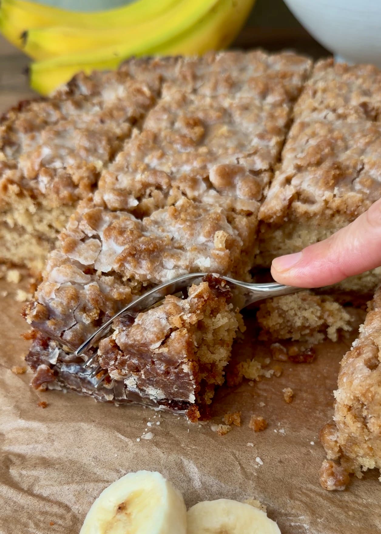 A fork pulling a bite from a piece of banana coffee cake