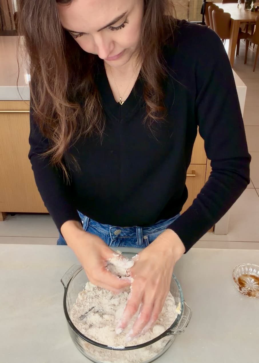Hands rubbing cold butter into the crumble ingredients