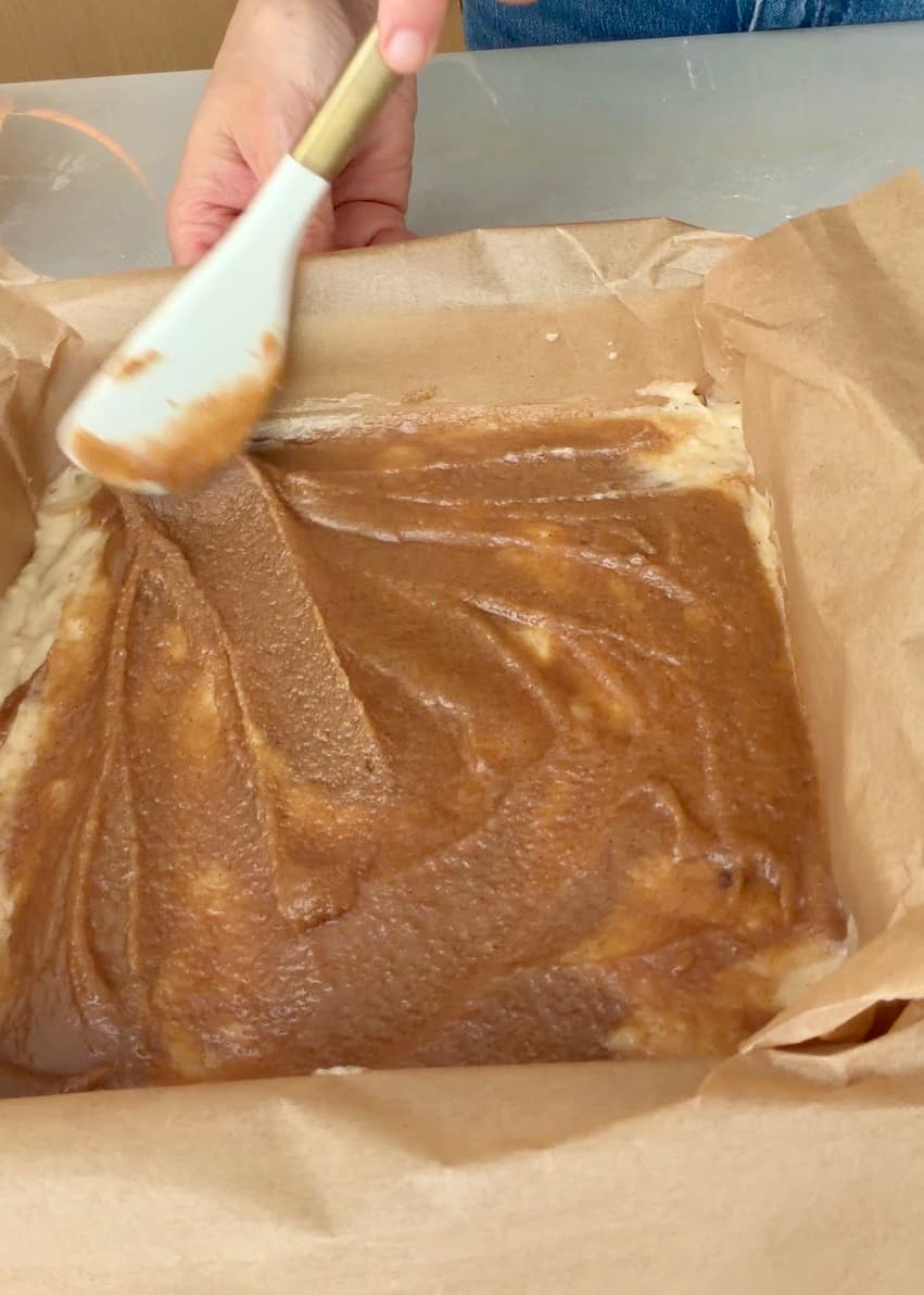 A close view of the cinnamon filling being smoothed into a thin layer
