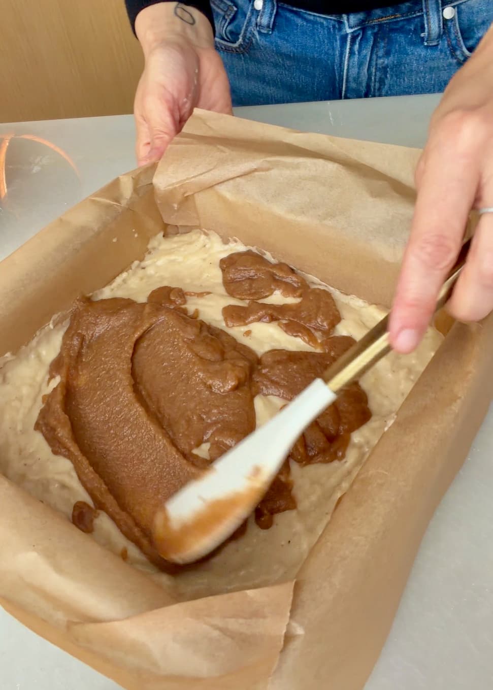 A spatula spreading the cinnamon filling over the banana batter