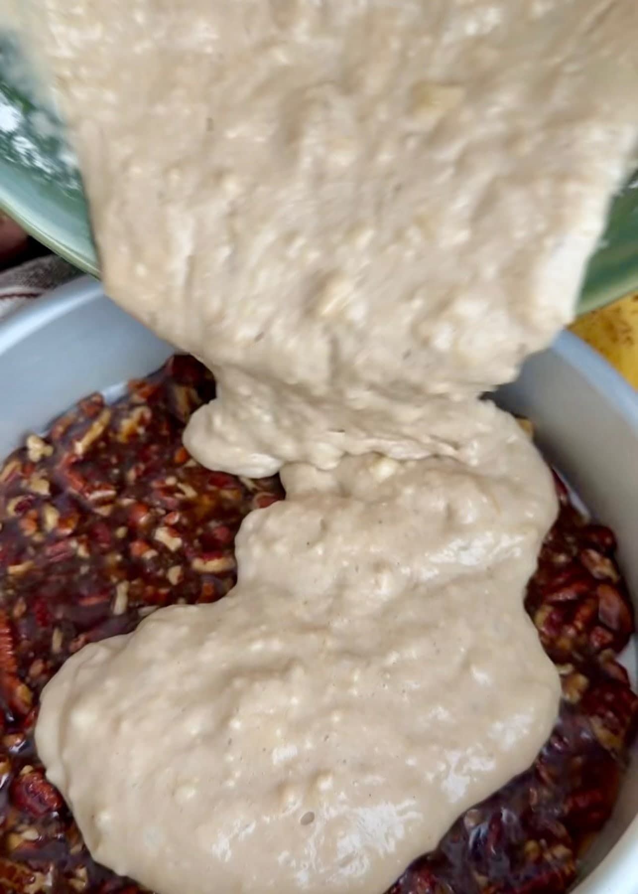 Banana cake batter being added over the pecan topping