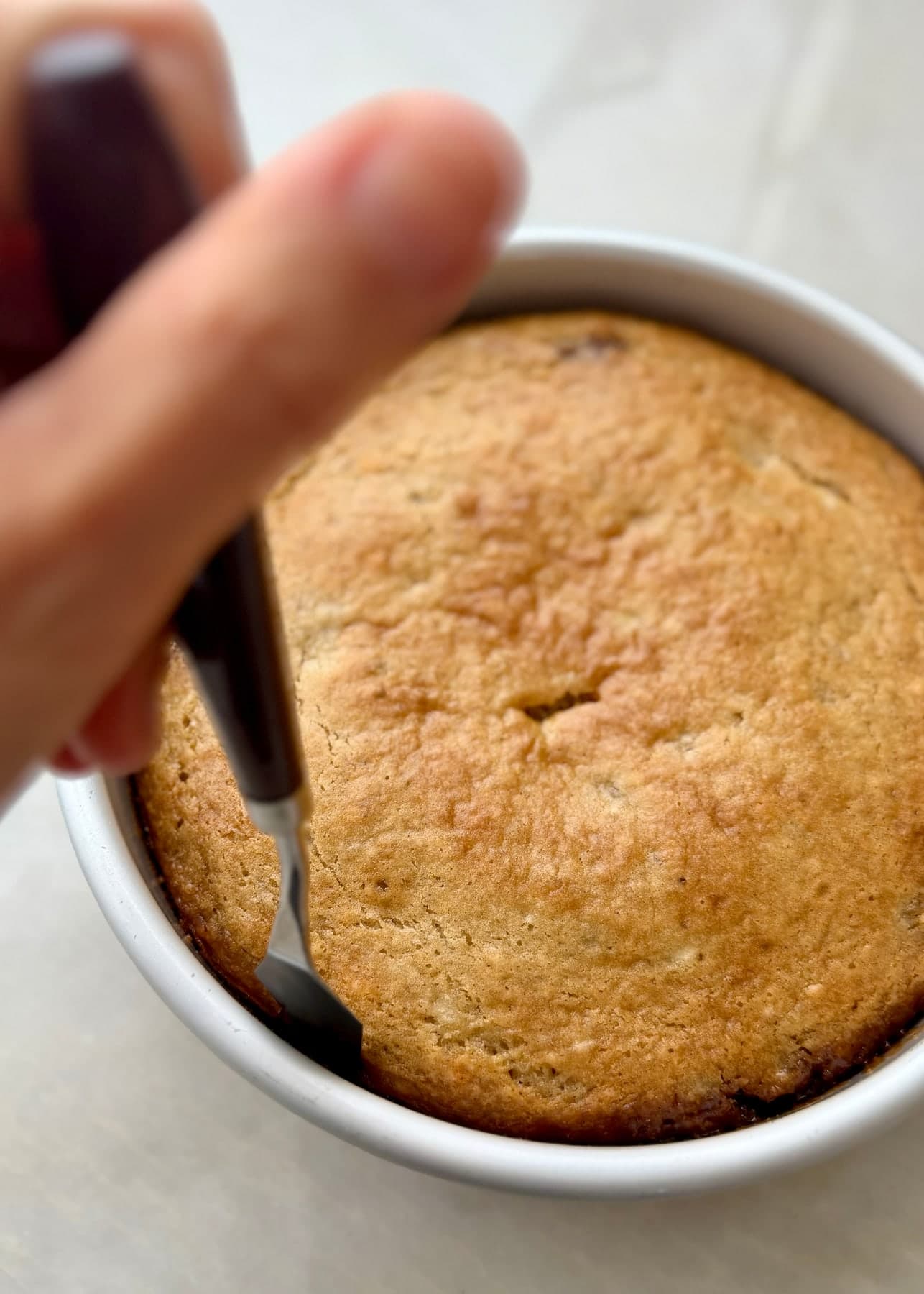 A thin spatula running between the baked cake and the round pan