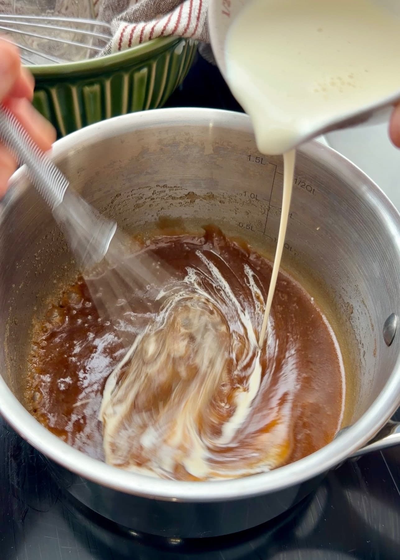 Cream pouring in a thin stream into the brown sugar mixture while it is whisked
