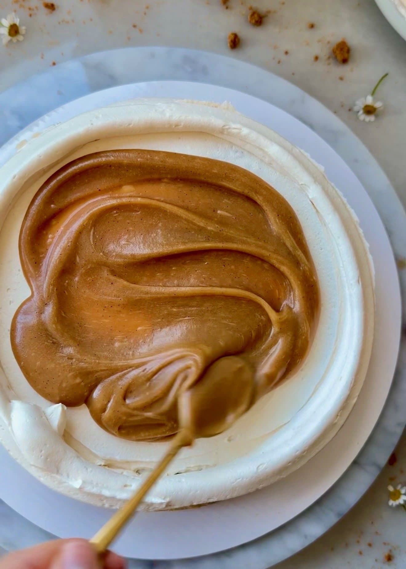 Glossy Biscoff filling spread over the center of a buttercream-coated cake layer