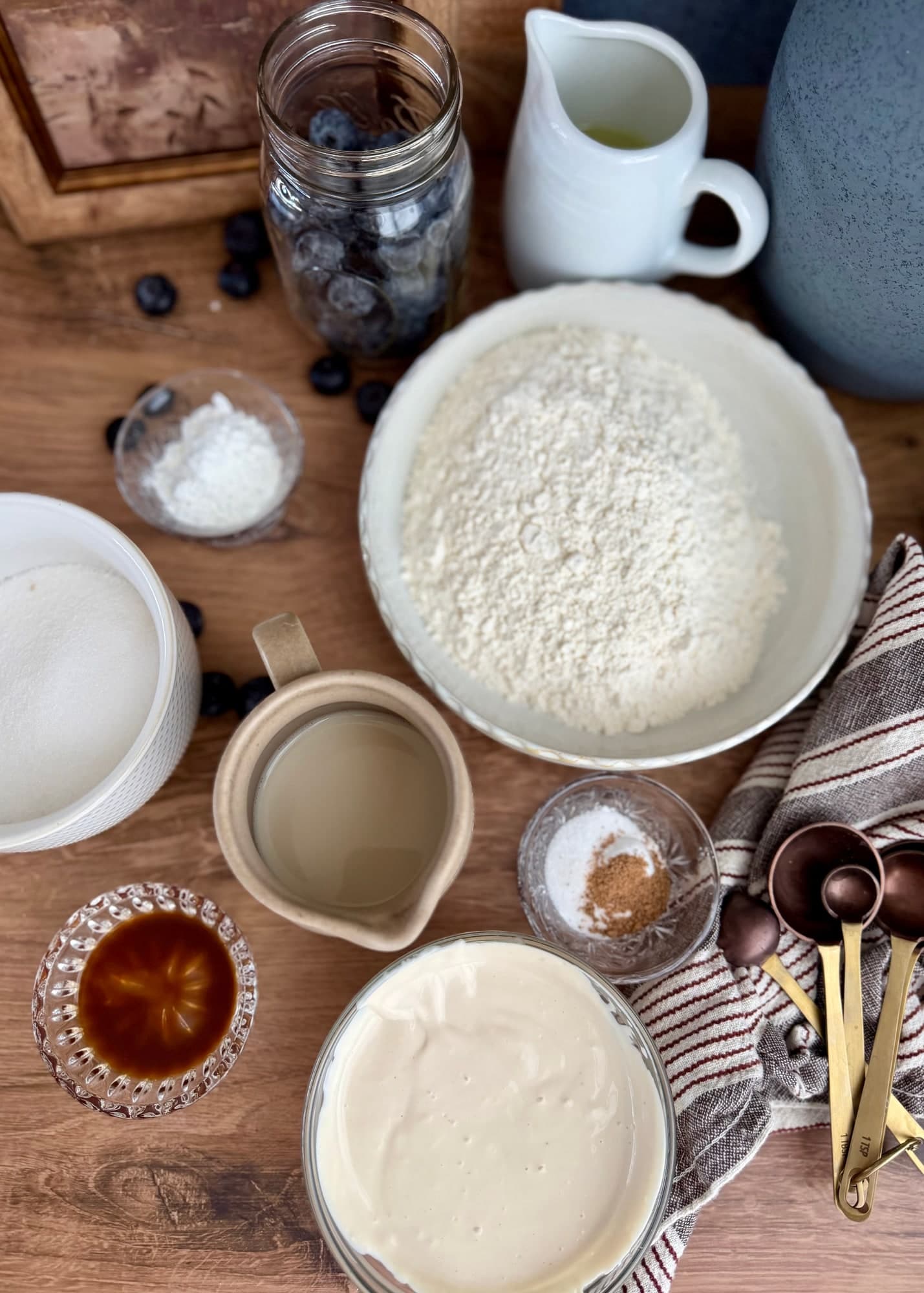 Flour, sugar, yogurt, milk, oil, and flavorings arranged for the blueberry cake