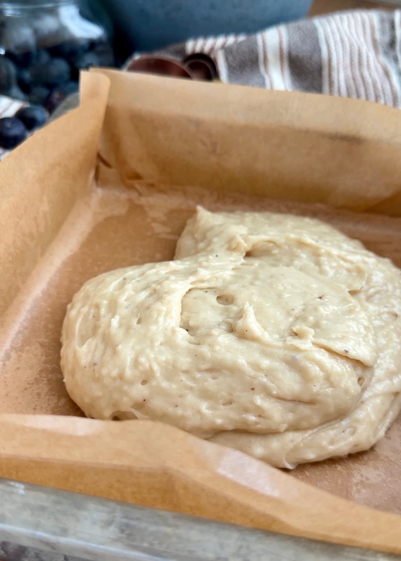 A mound of cake batter in the parchment-lined baking pan
