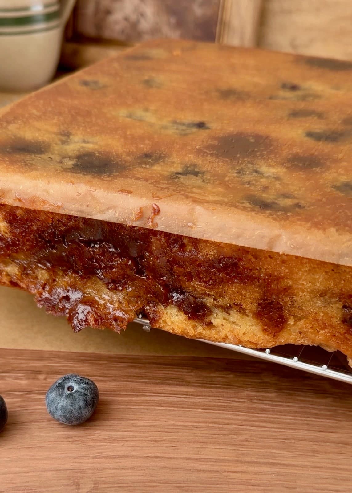 The inverted blueberry cake with parchment still covering its flat base