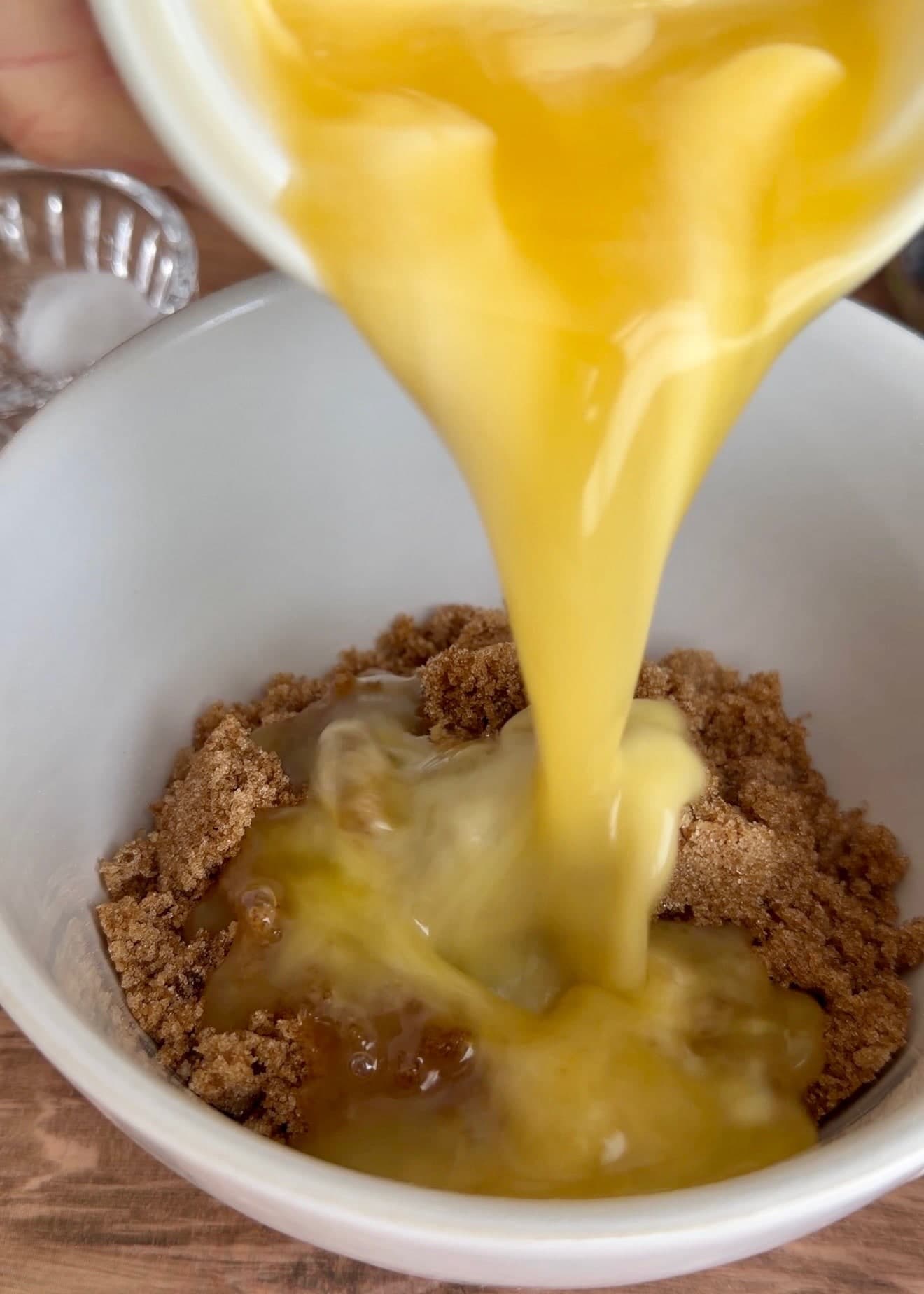 Melted butter pouring into a bowl of brown sugar
