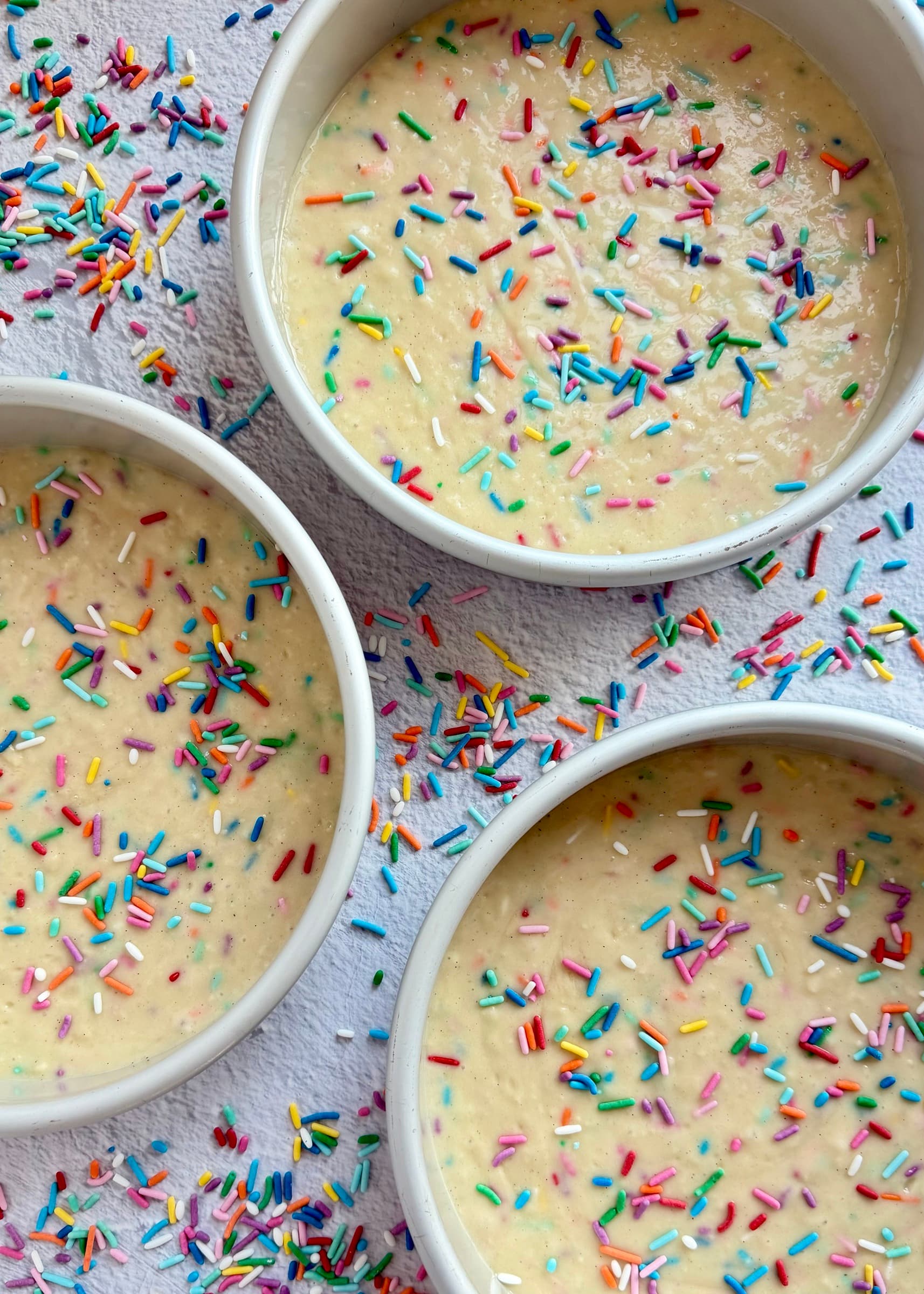 Funfetti cake batter divided among three round cake pans
