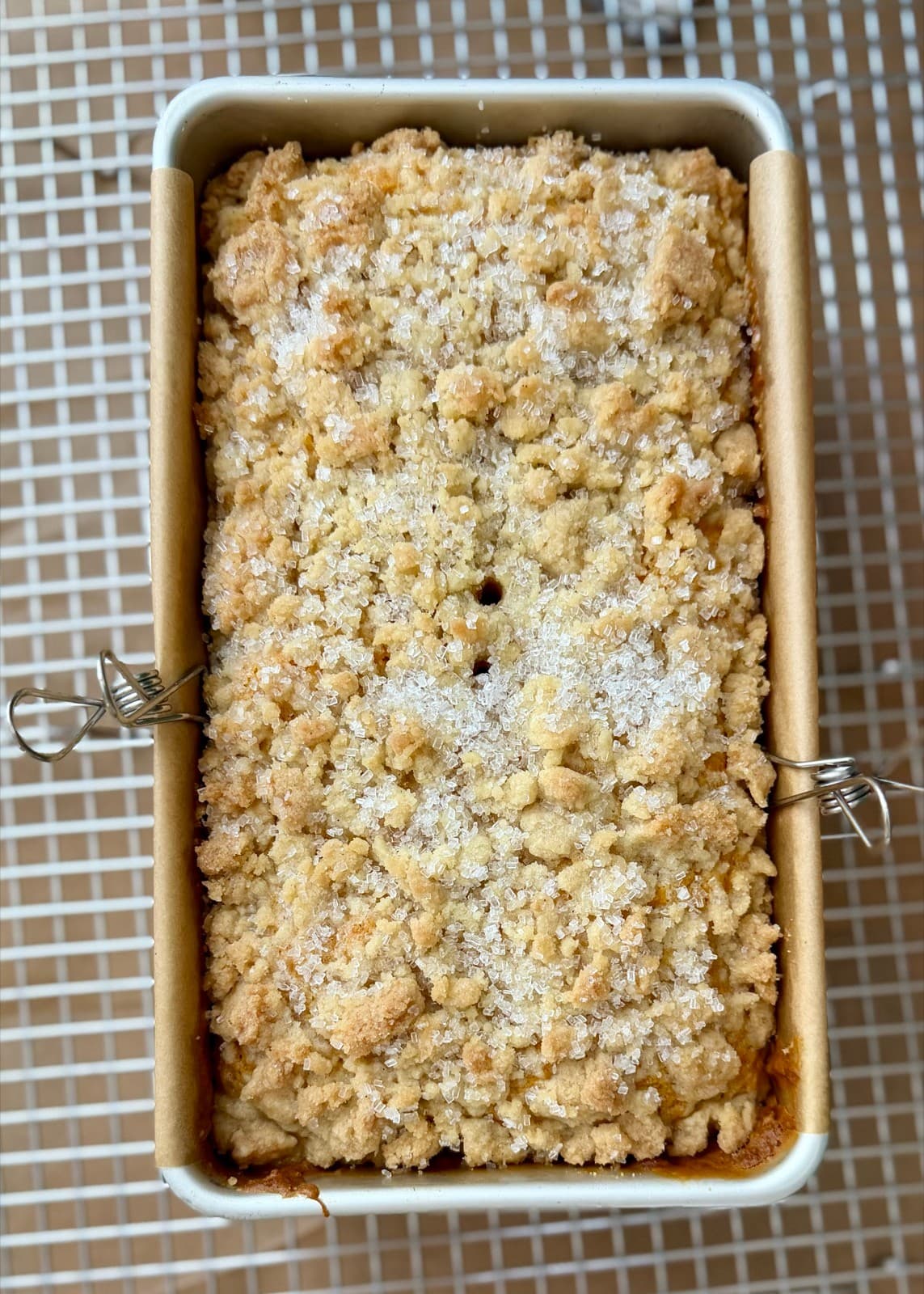 Baked carrot loaf in its pan with a golden streusel and sugar topping