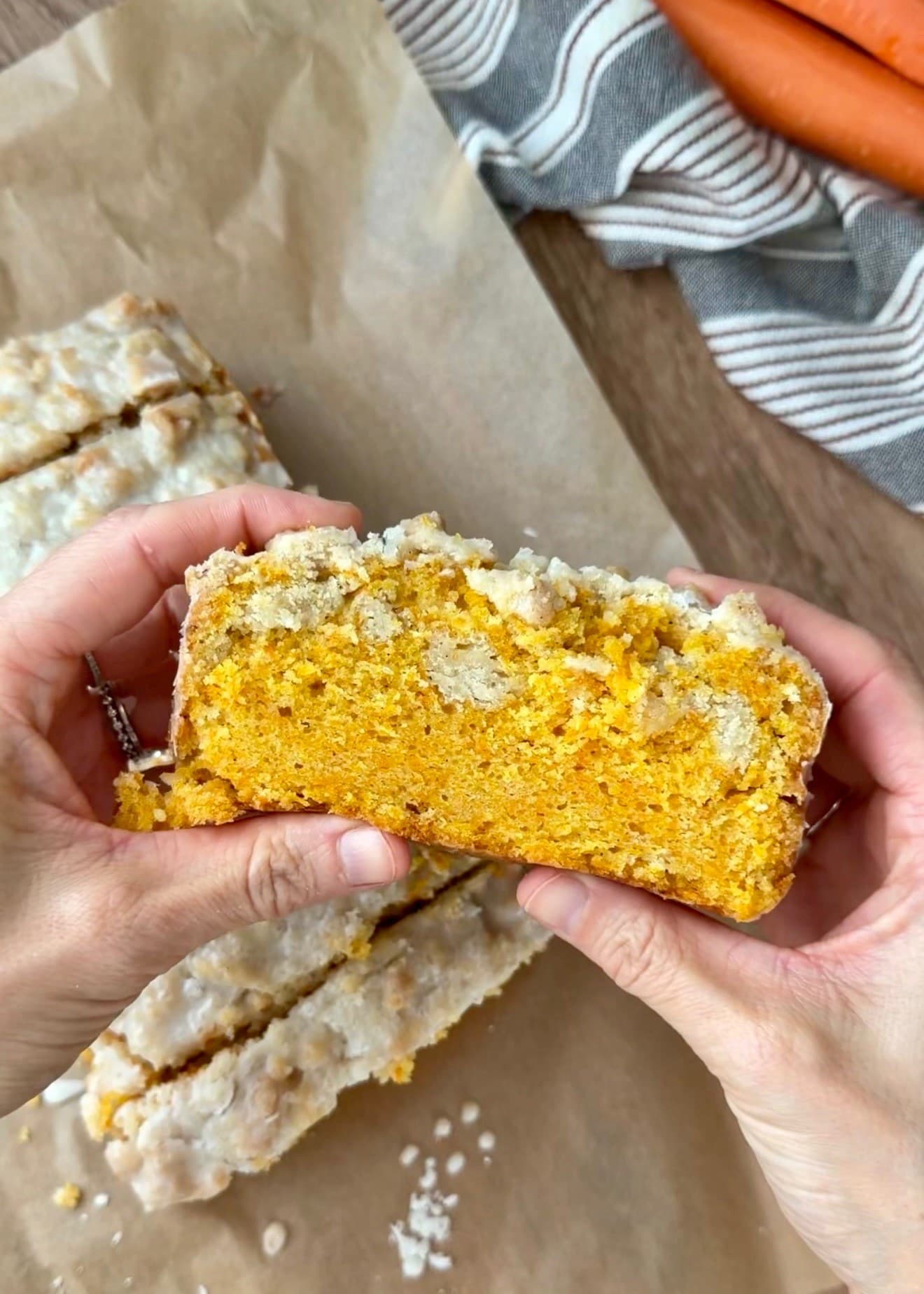 A slice held up to show the orange carrot crumb and pale streusel pockets