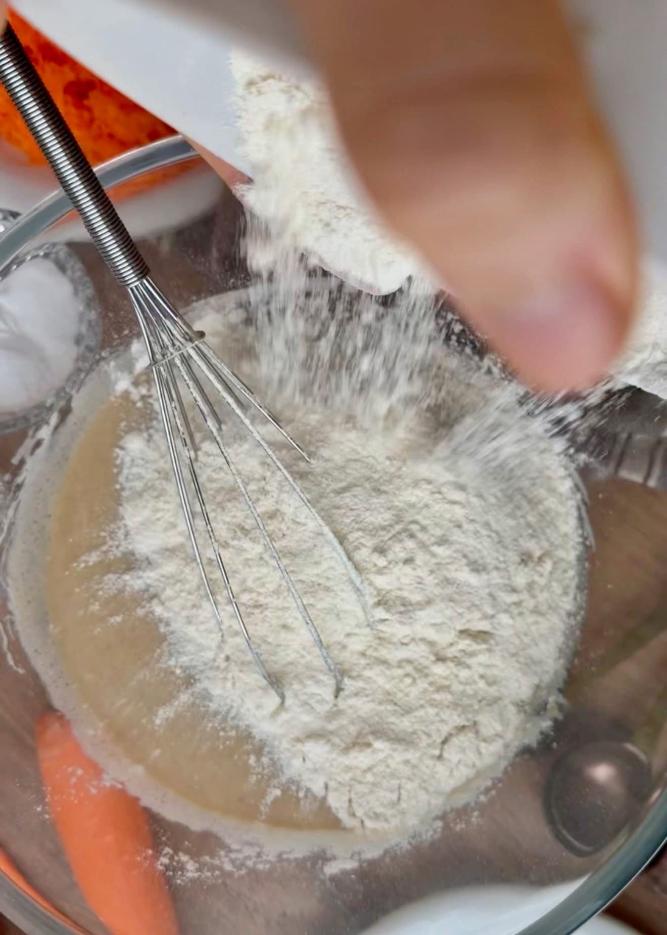 Flour added to the wet batter in a glass bowl