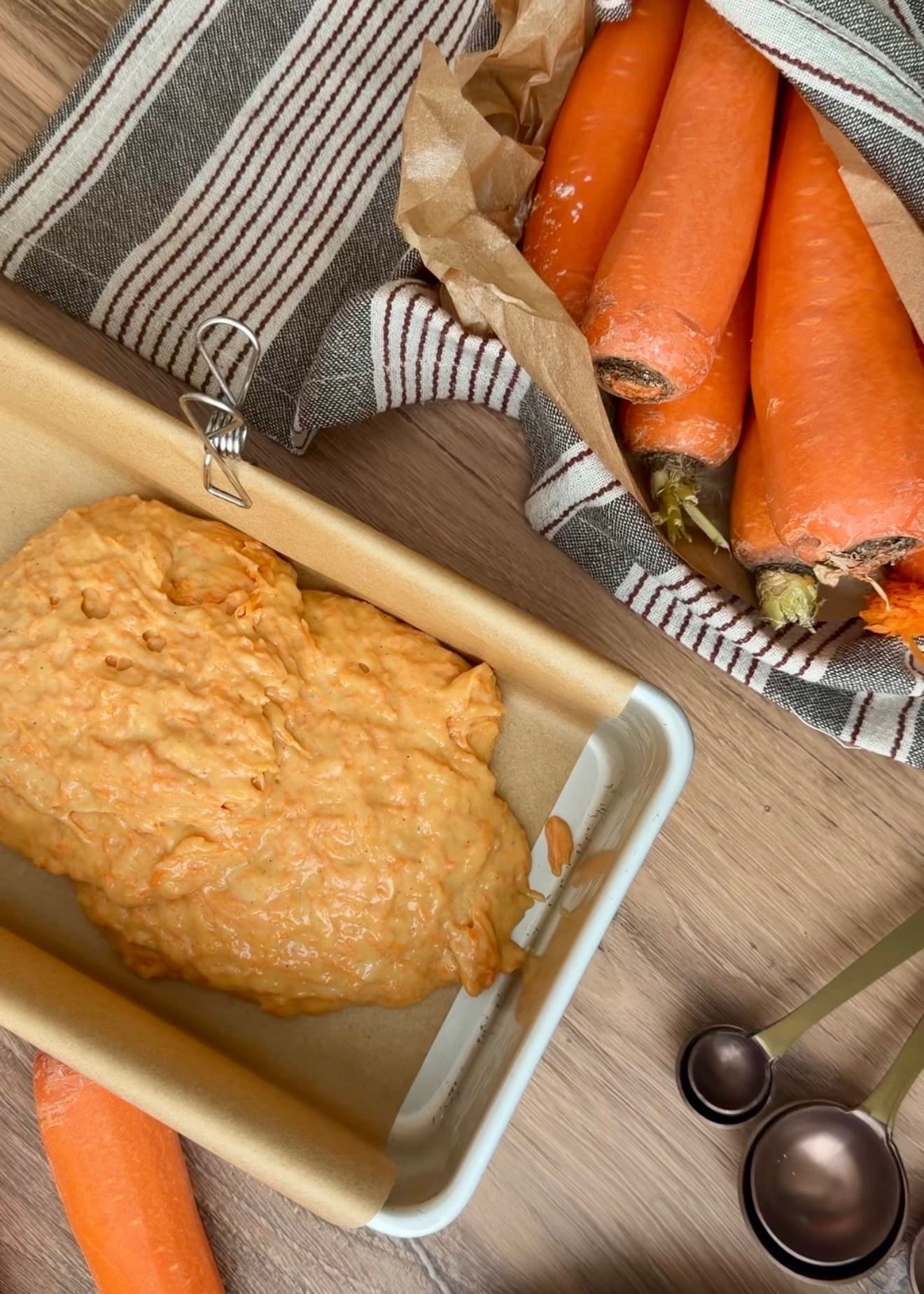 Carrot batter spooned into a parchment-lined loaf pan