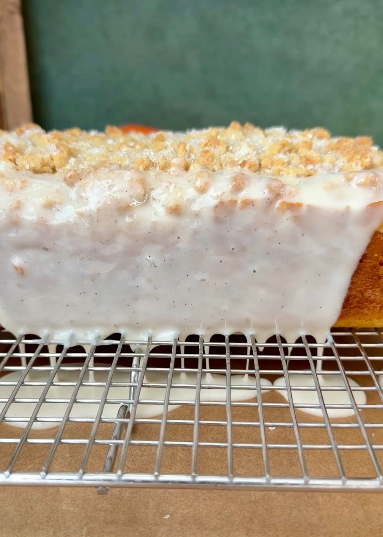 Vanilla glaze running down the sides of the loaf onto a tray below the rack