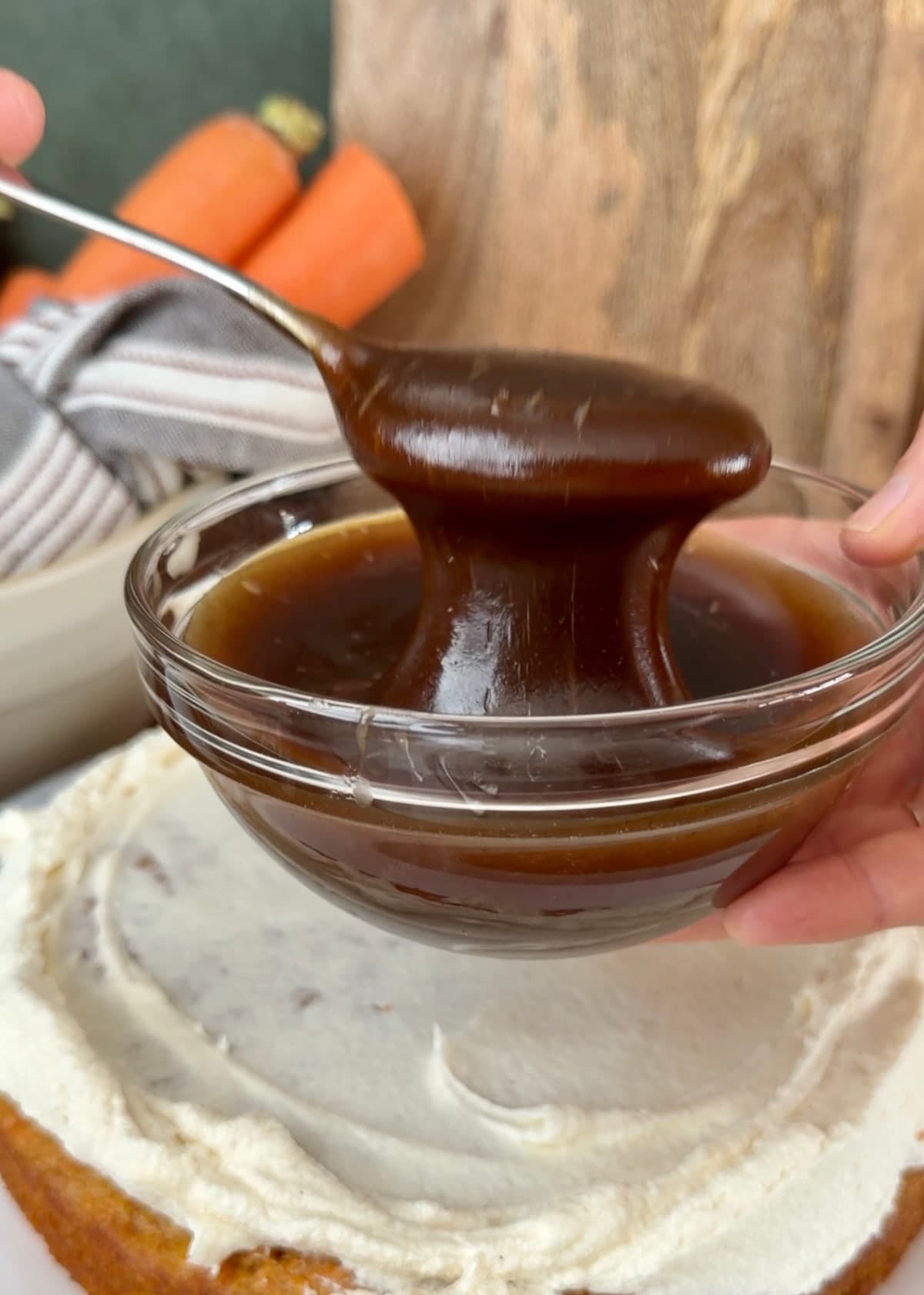 Thick cooled cinnamon filling falling from a spoon into a glass bowl