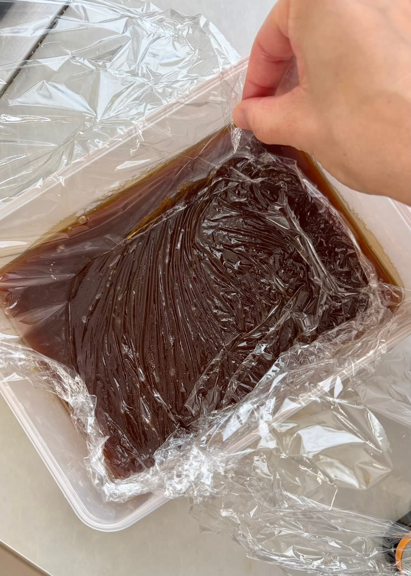 Plastic wrap lifted from the surface of cooled cinnamon filling
