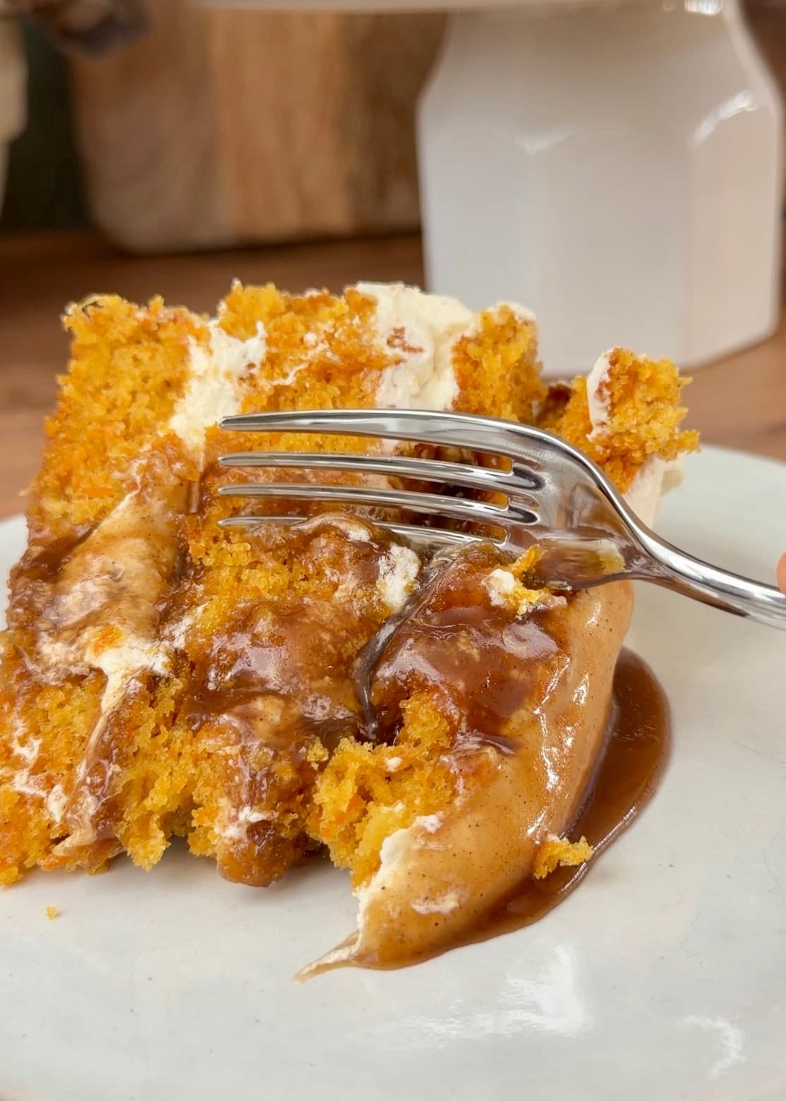 A fork cutting into carrot cake with soft cinnamon roll filling