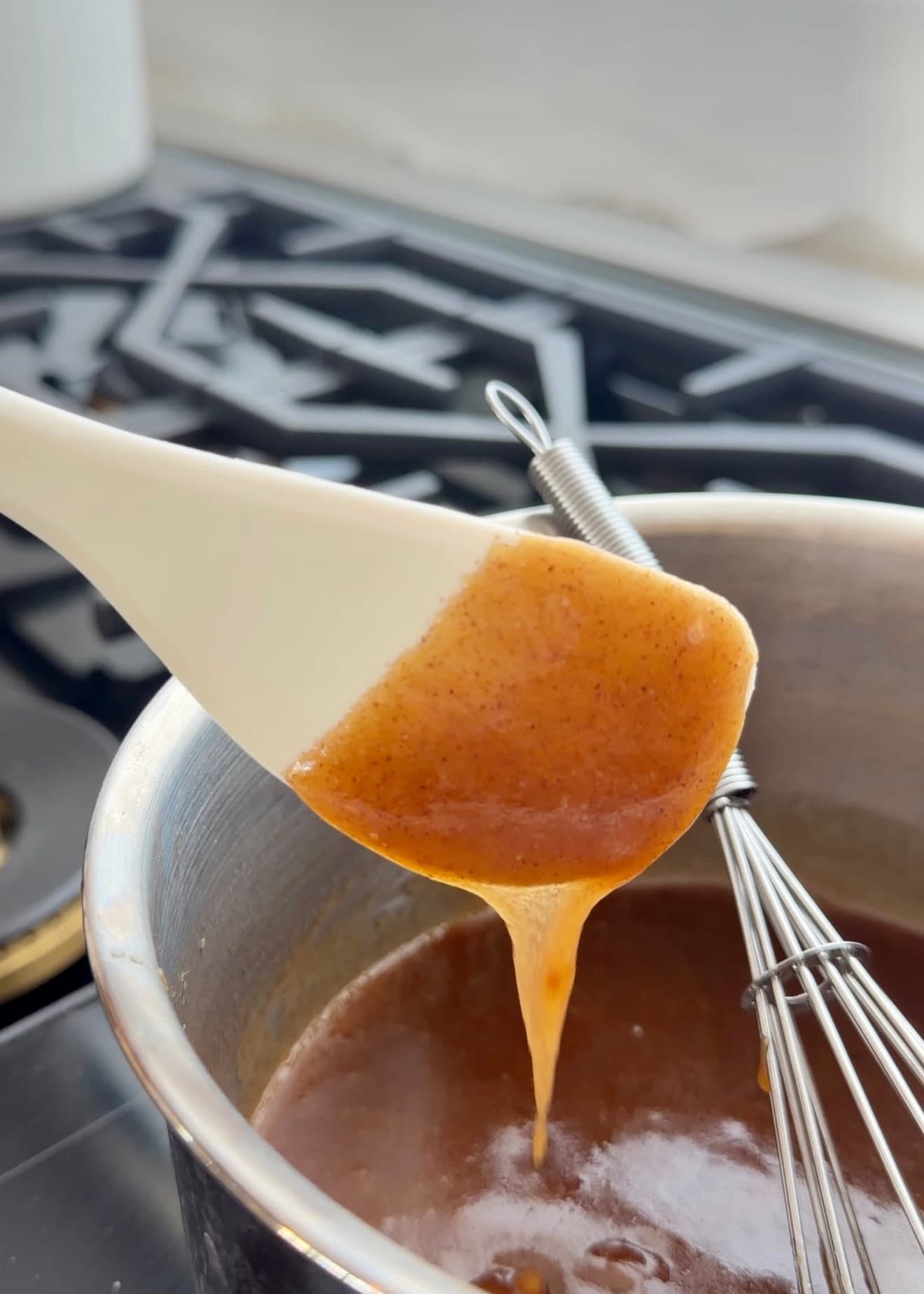 Cooked cinnamon roll lava coating a spatula in an amber ribbon