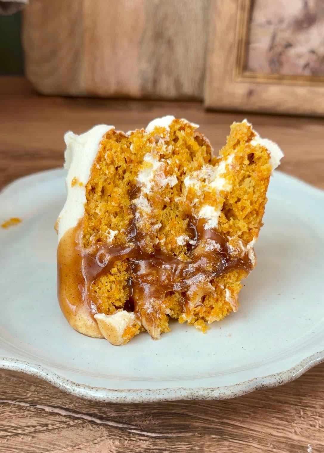 A slice of carrot cake with cream cheese frosting and cinnamon roll lava