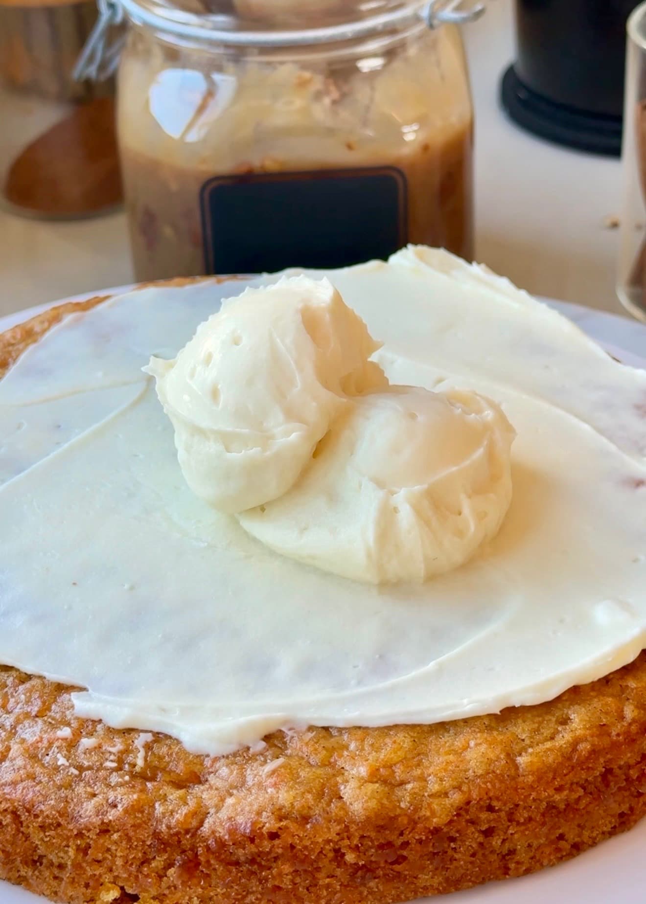 Silky cheesecake frosting spread over a carrot cake layer