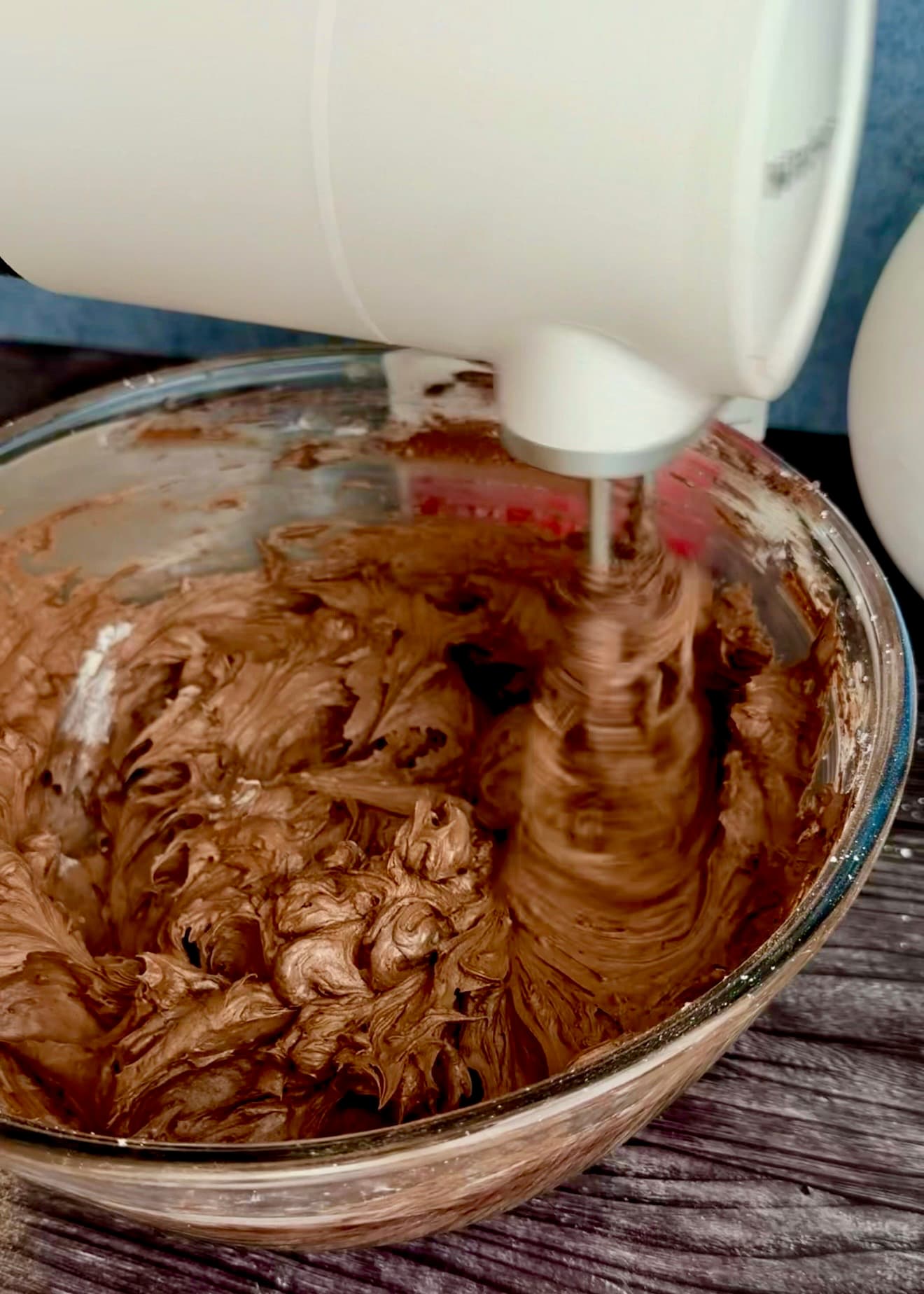 A hand mixer moving through smooth chocolate buttercream