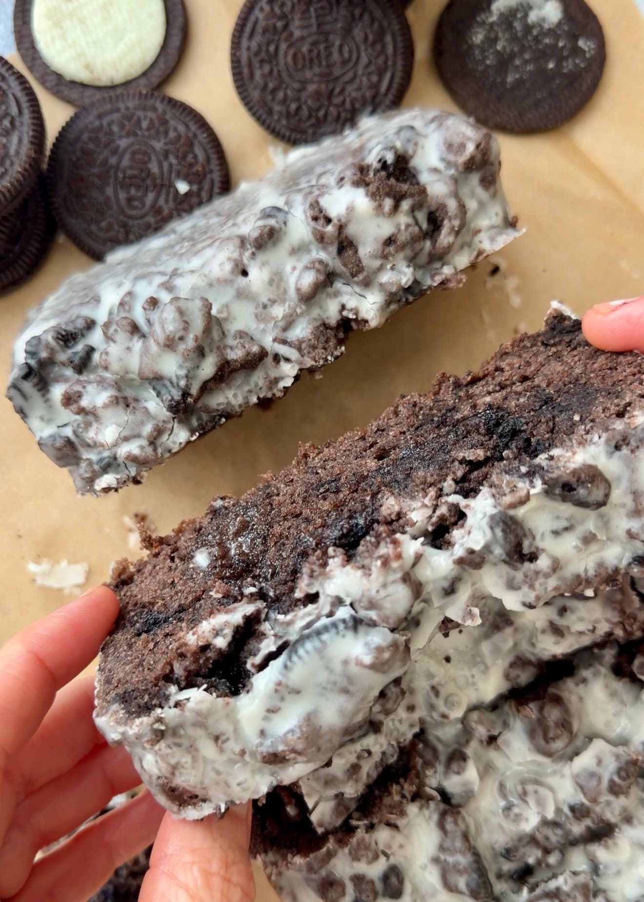 A slice of glazed chocolate Oreo loaf held over the remaining slices