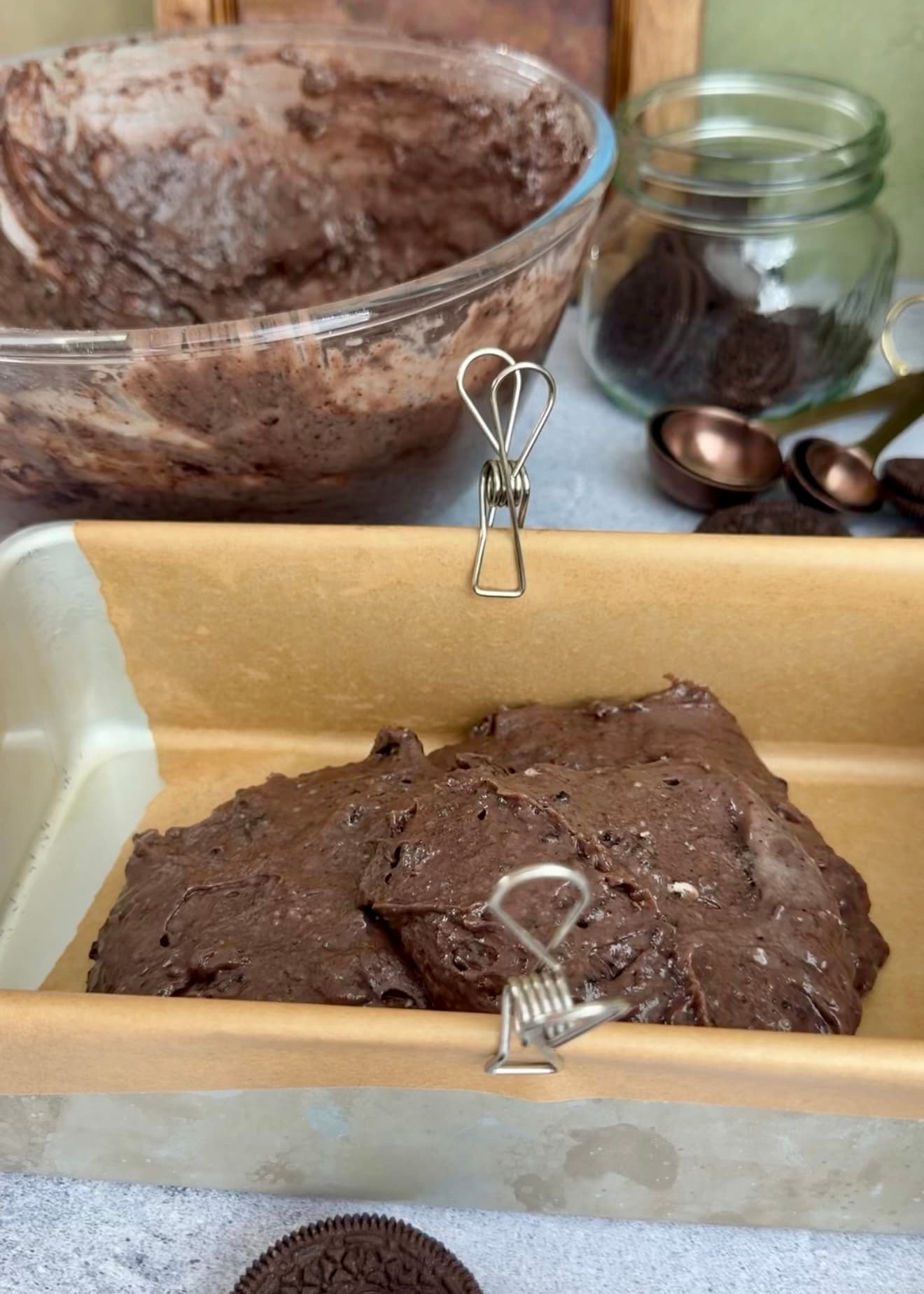 Chocolate batter spooned into a lined loaf pan