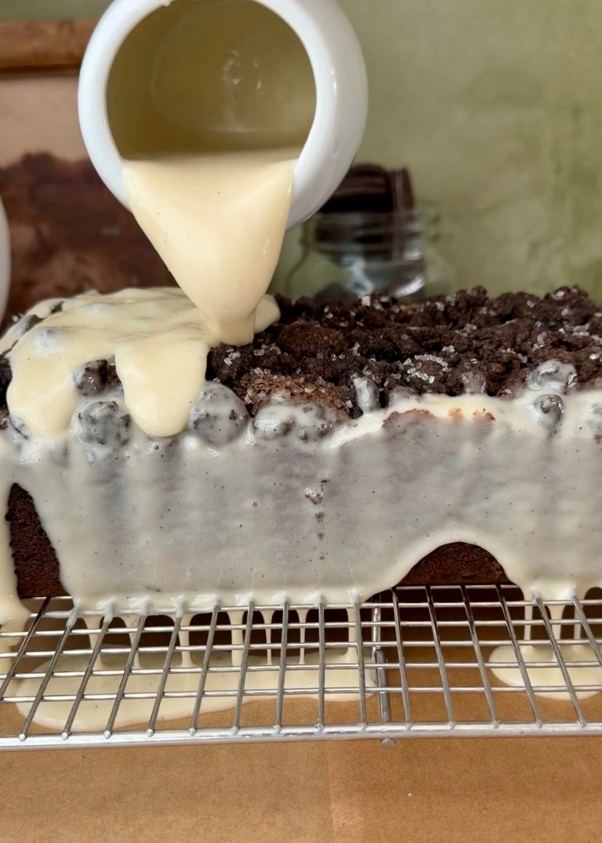 Vanilla glaze being poured from a pitcher over the loaf