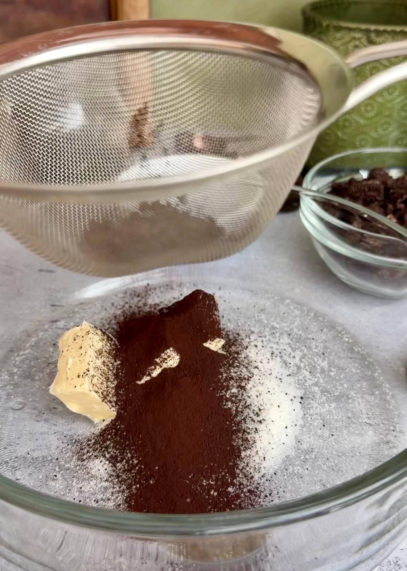 Cocoa sifted into a bowl containing butter and dry ingredients