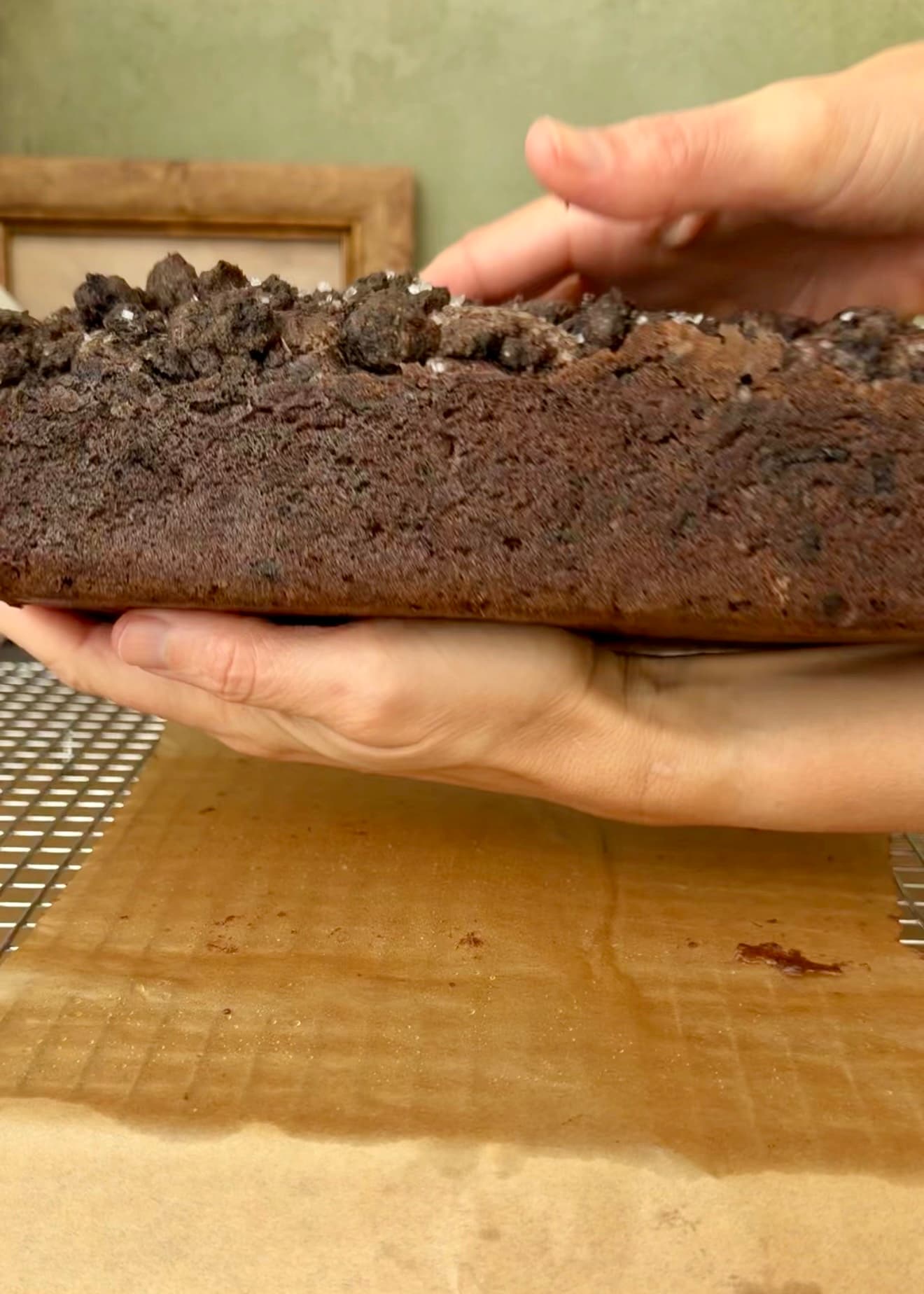 Hands supporting the unglazed loaf from underneath